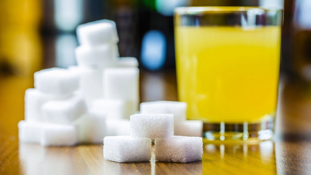 ein Glas mit Saft und viel Würfelzucker sind auf einem Tisch