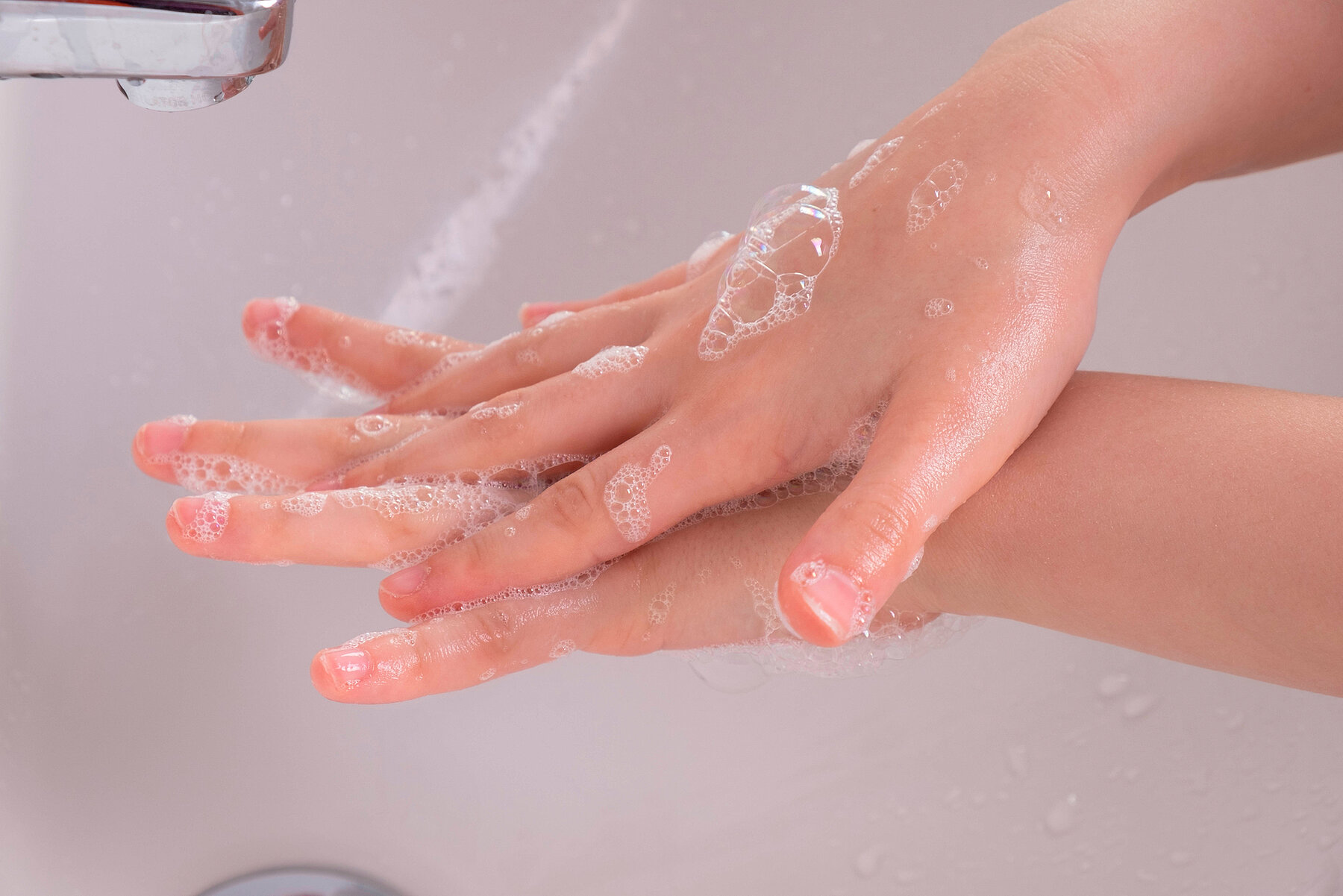 young girl soaped her hands and holds them under the tap in the bathroom young girl soaped her hands and holds them under the tap in the bathroom in the morning