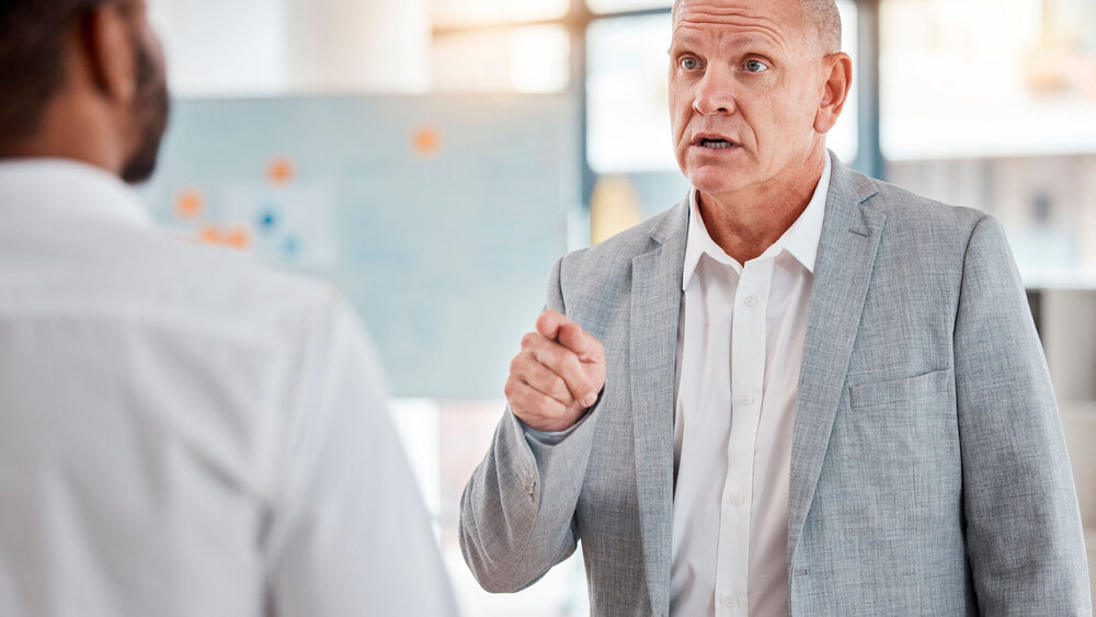Aggressiver Mann beschwert sich lautstark bei Arzt im Behandlungszimmer.
