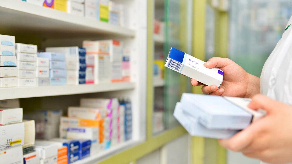Pharmacist holding medicine box in pharmacy drugstore.