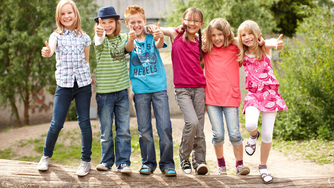Gruppe fröhlicher Kinder auf Baumstamm