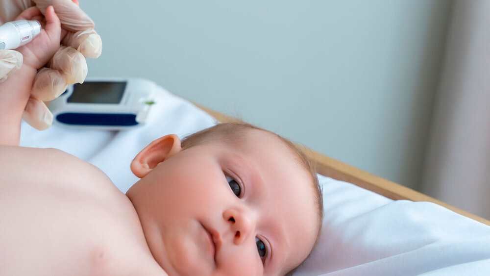 Ärztin prüft Blutzuckerspiegel eines Säuglings