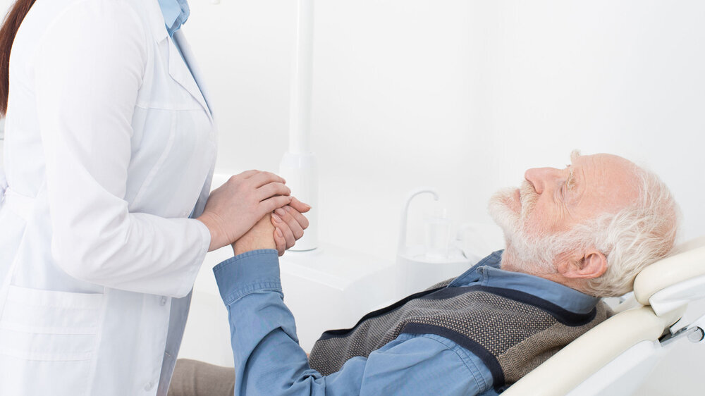Liegender Patient hält die Hand des Zahnarztes Liegender Patient hält die Hand des Zahnarztes