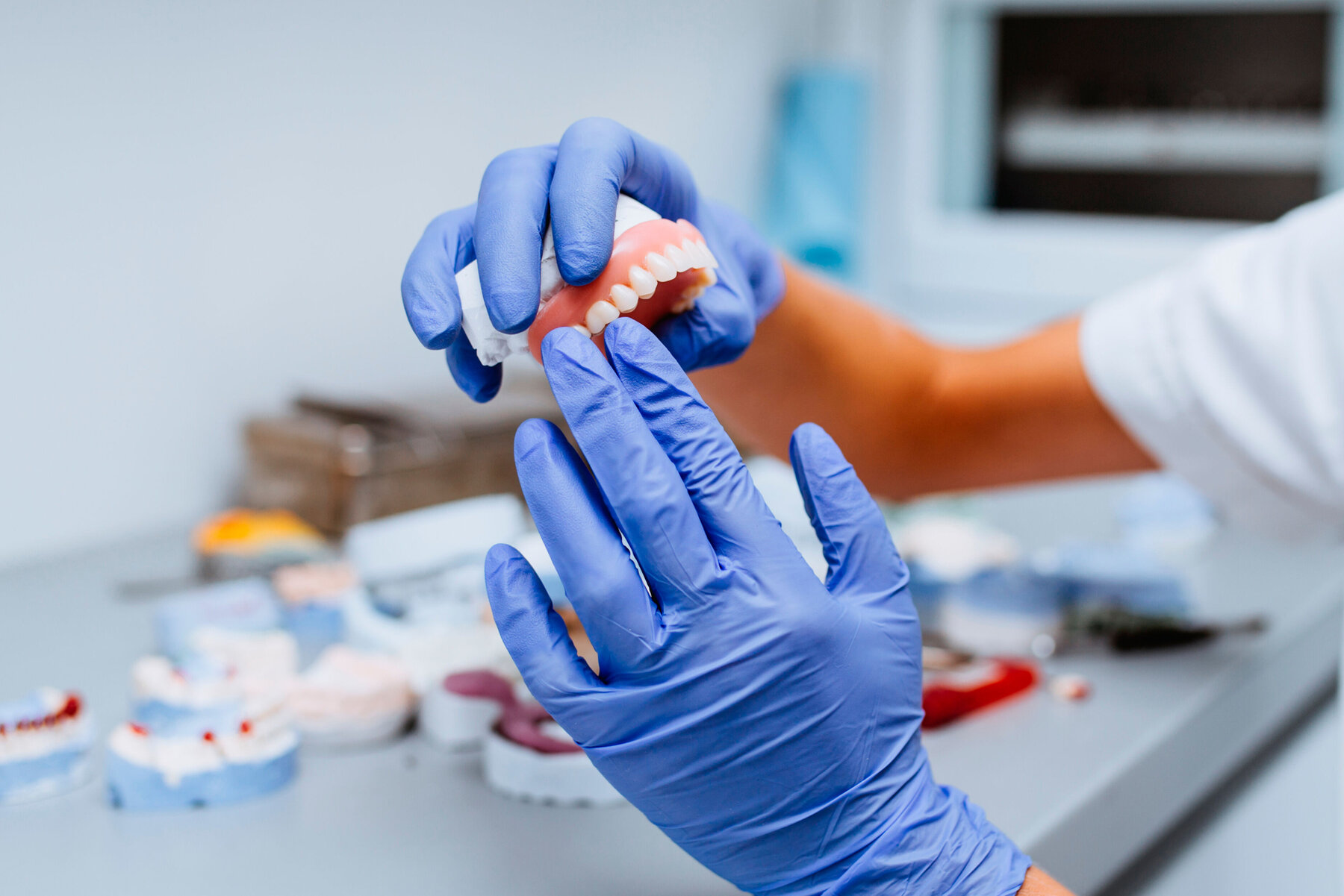 Dental prosthesis, prosthetics work. Close up of prosthetic's hands while working on the denture. Selective focus. Dental prosthesis, prosthetics work. Close up of prosthetic's hands while working on the denture. Selective focus.