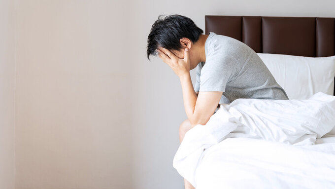Gestresster oder depressiver Mann stützt auf dem Bett sitzend den Kopf in die Hände Gestresster oder depressiver Mann stützt auf dem Bett sitzend den Kopf in die Hände